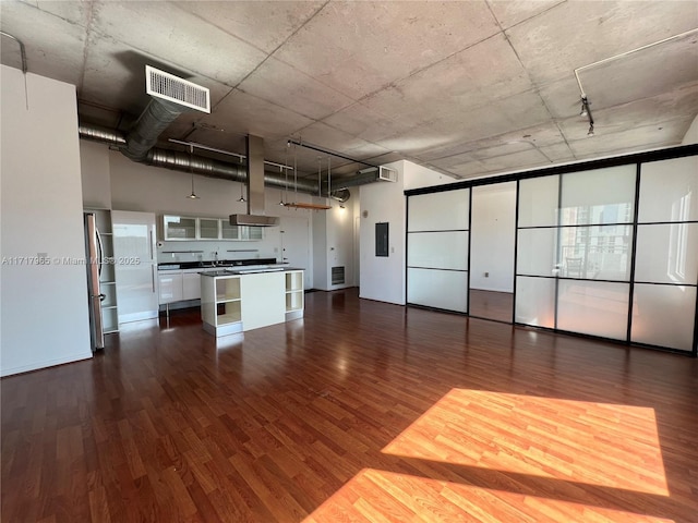 interior space featuring wood-type flooring, a towering ceiling, sink, and electric panel