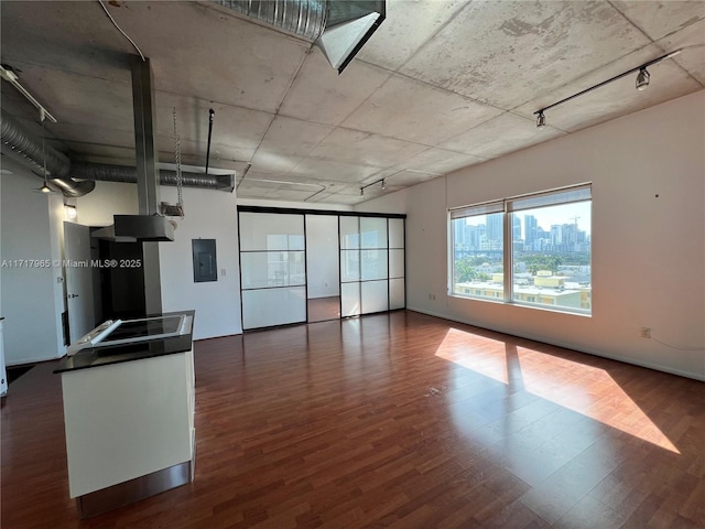 interior space with track lighting, dark hardwood / wood-style flooring, and electric panel