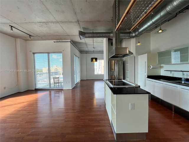 kitchen featuring white cabinetry, wall chimney range hood, dark wood-type flooring, and stainless steel fridge