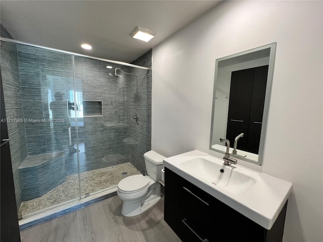 bathroom featuring hardwood / wood-style flooring, vanity, toilet, and walk in shower