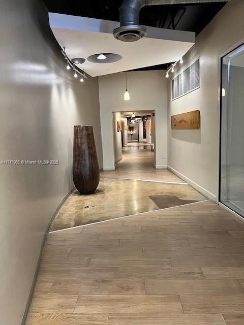 corridor featuring rail lighting and light hardwood / wood-style floors