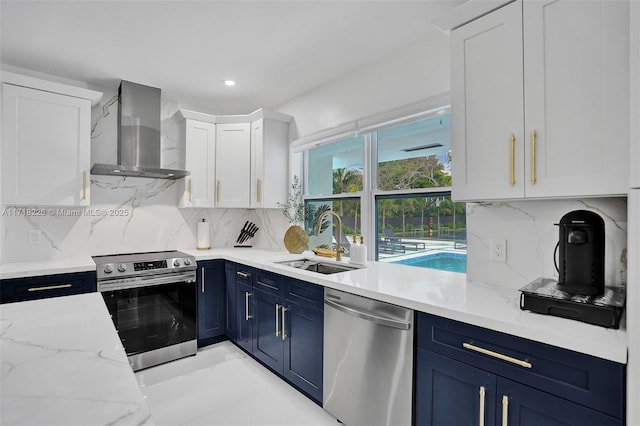 kitchen with appliances with stainless steel finishes, tasteful backsplash, sink, wall chimney range hood, and white cabinetry