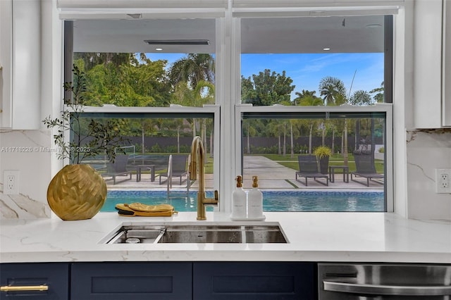 interior space with dishwashing machine, tasteful backsplash, blue cabinetry, and sink