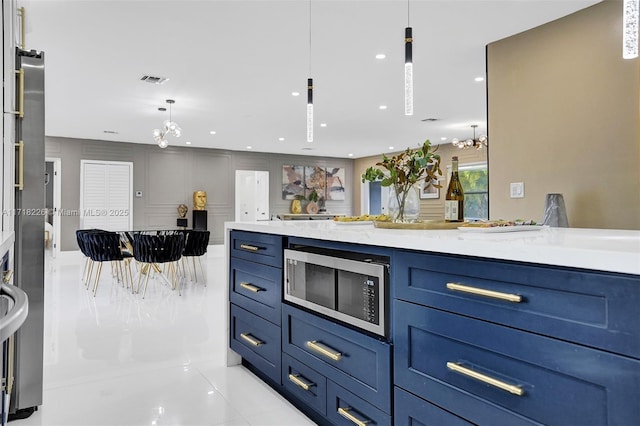 kitchen featuring blue cabinetry, light stone counters, light tile patterned floors, and hanging light fixtures