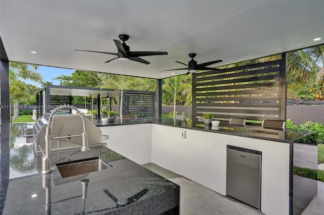 view of patio / terrace featuring grilling area, ceiling fan, a bar, and exterior kitchen