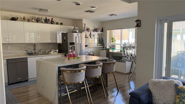 kitchen featuring backsplash, a center island, a breakfast bar, stainless steel appliances, and white cabinets