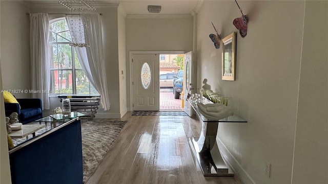 entrance foyer featuring ornamental molding, light hardwood / wood-style floors, and plenty of natural light