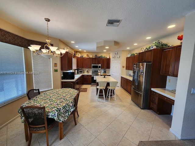 dining space with a notable chandelier, light tile patterned floors, and a textured ceiling