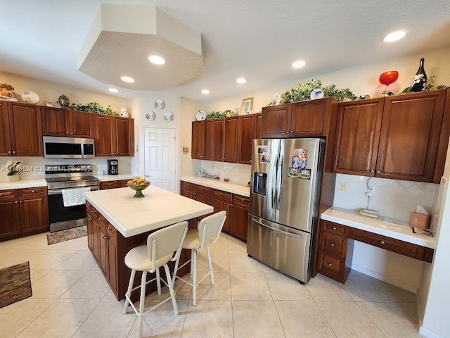 kitchen with a center island, light tile patterned floors, tasteful backsplash, a kitchen bar, and stainless steel appliances