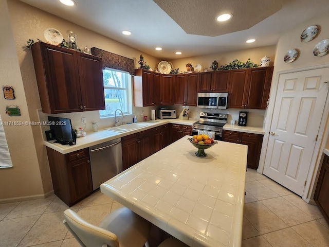 kitchen featuring light tile patterned flooring, stainless steel appliances, tile countertops, and sink