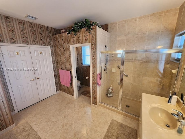 bathroom featuring tile patterned floors, vanity, toilet, and a shower with door