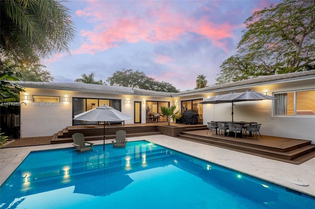 pool at dusk featuring a deck