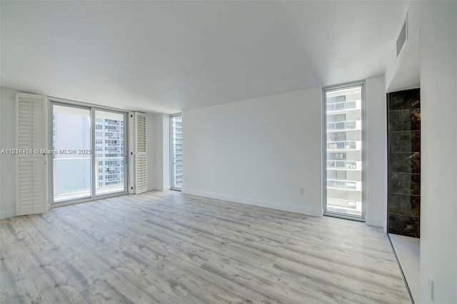 spare room featuring expansive windows and light hardwood / wood-style floors