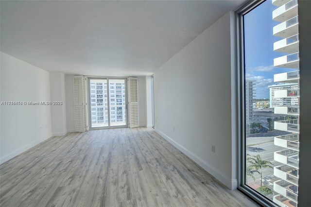 spare room with light hardwood / wood-style floors and a wall of windows