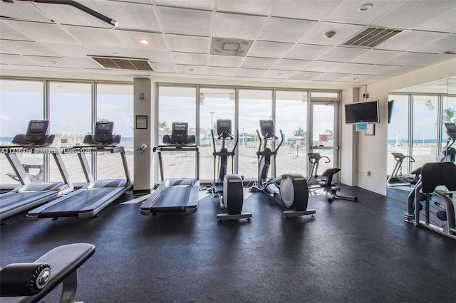 gym with a drop ceiling and a wall of windows