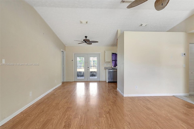 unfurnished living room featuring vaulted ceiling, light wood-type flooring, ceiling fan, and french doors