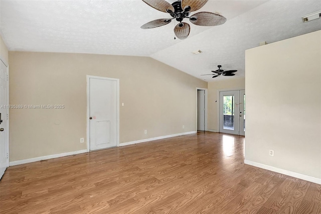 empty room featuring a textured ceiling, light hardwood / wood-style flooring, french doors, lofted ceiling, and ceiling fan