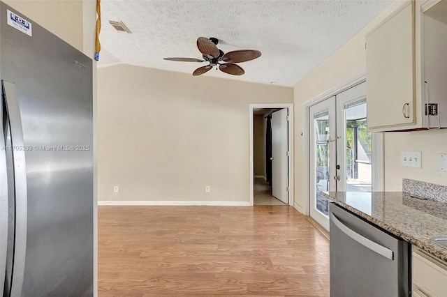 kitchen with light stone counters, a textured ceiling, dishwasher, french doors, and lofted ceiling