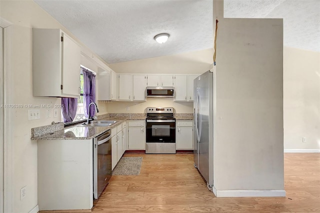 kitchen with appliances with stainless steel finishes, light hardwood / wood-style floors, light stone countertops, white cabinets, and sink