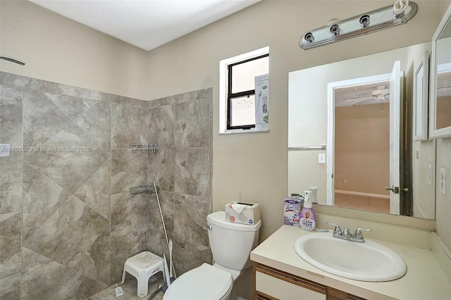 bathroom with toilet, a tile shower, and vanity