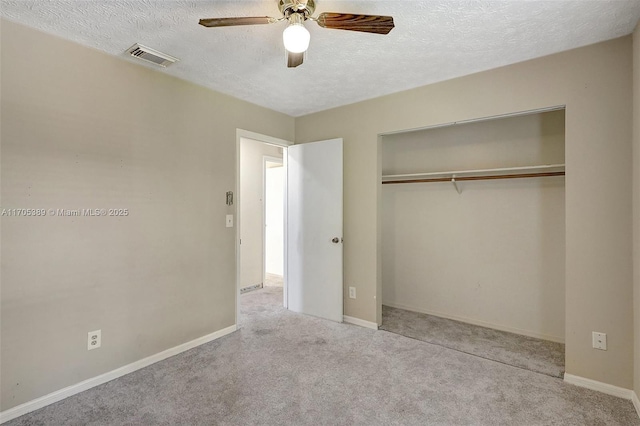 unfurnished bedroom featuring a textured ceiling, ceiling fan, a closet, and light carpet