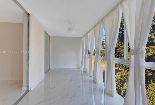 unfurnished sunroom featuring ceiling fan