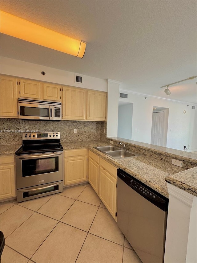 kitchen featuring visible vents, light brown cabinetry, light tile patterned flooring, stainless steel appliances, and a sink