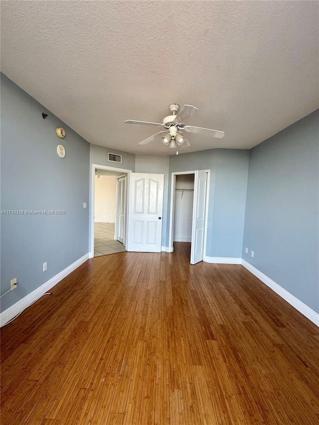 unfurnished bedroom featuring a closet, visible vents, baseboards, and wood finished floors