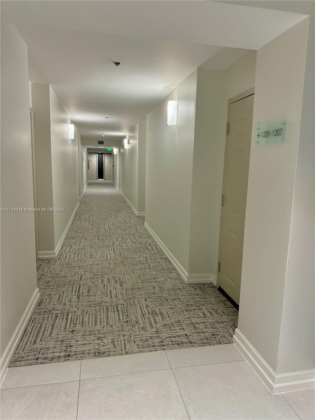 corridor with baseboards and tile patterned flooring