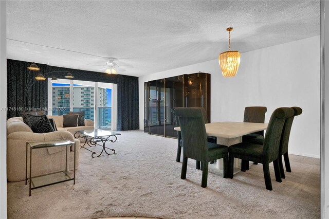 dining space with a textured ceiling, light carpet, and ceiling fan with notable chandelier