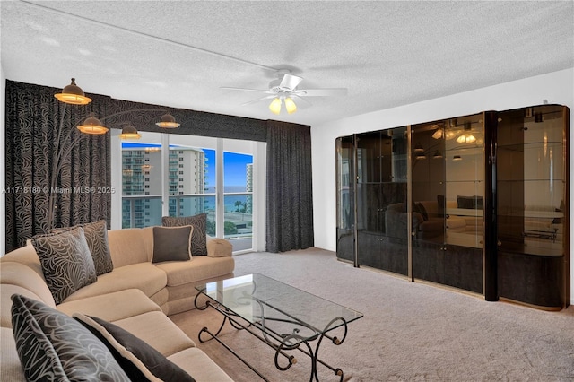 living room with a textured ceiling, carpet floors, and ceiling fan