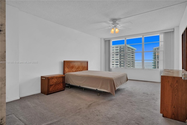 carpeted bedroom featuring ceiling fan and a textured ceiling