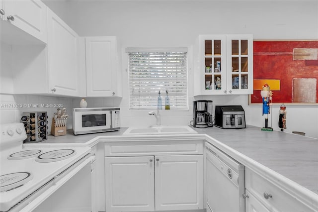 kitchen with tasteful backsplash, white cabinetry, sink, and white appliances