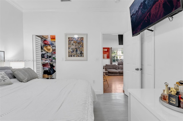 bedroom featuring wood-type flooring, a closet, and crown molding