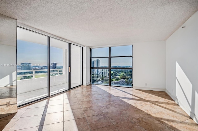 spare room featuring baseboards, a textured ceiling, floor to ceiling windows, and a city view