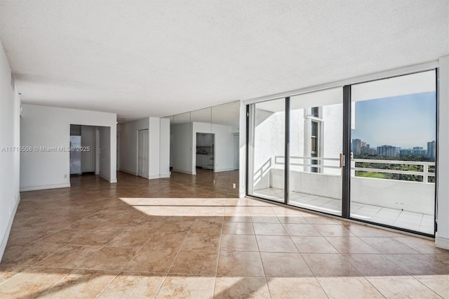 empty room with a view of city, expansive windows, a textured ceiling, and baseboards