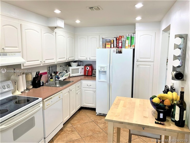 kitchen featuring white appliances, sink, light tile patterned floors, white cabinets, and range hood