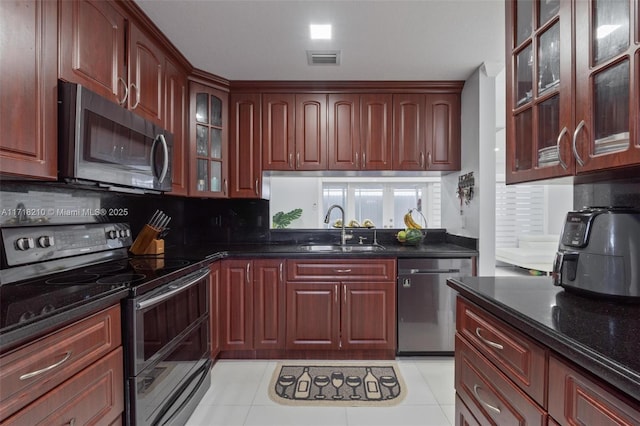 kitchen featuring light tile patterned floors, sink, appliances with stainless steel finishes, and dark stone counters