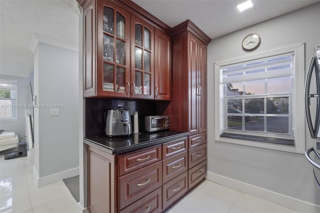 bar with dark stone countertops, light tile patterned floors, and crown molding