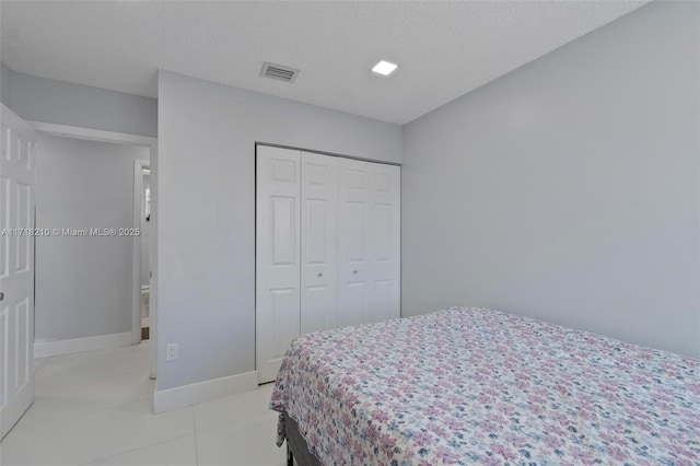 bedroom with light tile patterned flooring, a textured ceiling, and a closet