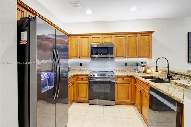 kitchen with backsplash, sink, light tile patterned floors, appliances with stainless steel finishes, and light stone counters