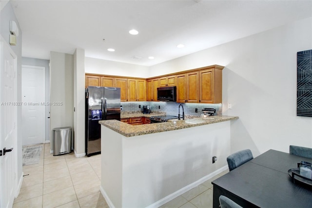 kitchen with light stone countertops, kitchen peninsula, backsplash, black appliances, and light tile patterned floors