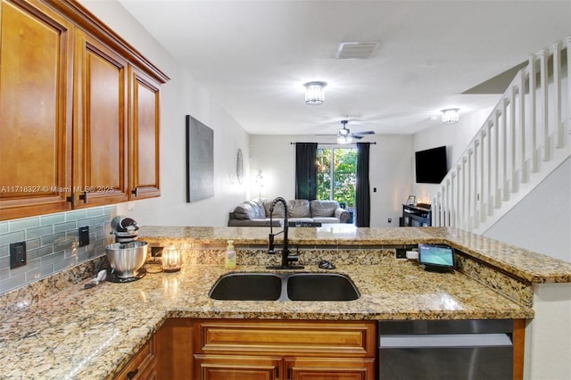 kitchen with ceiling fan, sink, light stone countertops, tasteful backsplash, and kitchen peninsula