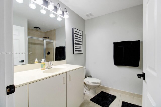 bathroom featuring tile patterned flooring, vanity, a shower with door, and toilet