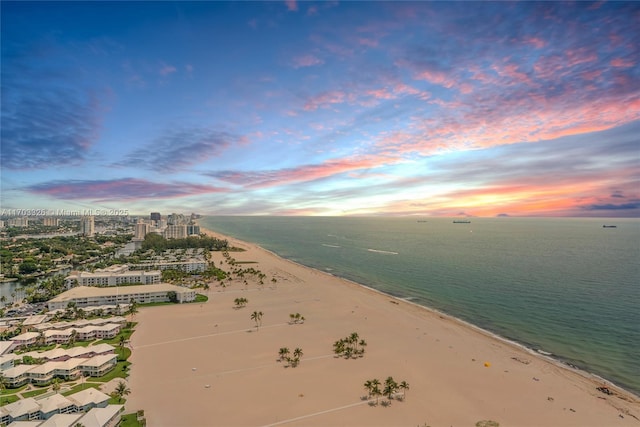 aerial view at dusk featuring a water view and a beach view