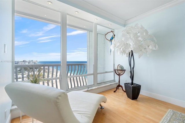 sitting room with a water view, wood-type flooring, and ornamental molding