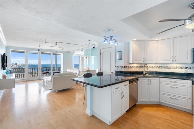 kitchen featuring sink, a water view, light hardwood / wood-style flooring, dishwasher, and white cabinetry