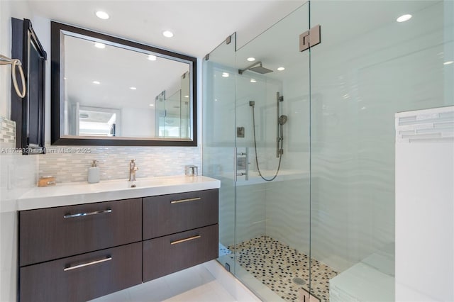 bathroom with backsplash, a shower with door, and vanity