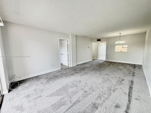 empty room featuring carpet flooring, a textured ceiling, and a chandelier