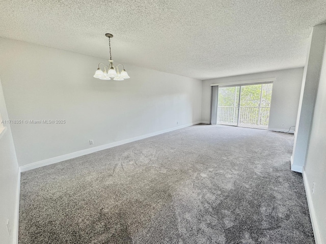 carpeted empty room with a textured ceiling and a notable chandelier